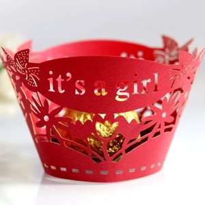 Pink laser cut cupcake wrappers with it's a girl text for baby shower decorations