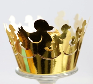 Close-up of laser-cut gold cupcake liners with a duck silhouette pattern and shiny finish