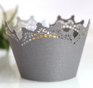 Detail of silver crown cupcake wrapper with intricate laser-cut patterns and pearly finish
