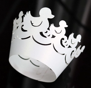 Macro view of white laser-cut duck silhouette cupcake wrapper with pearlescent finish