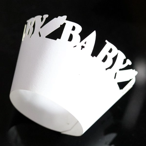 Macro shot of white laser-cut cupcake wrapper featuring BABY text and milk bottle design