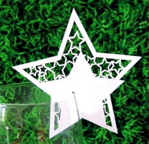 Laser-cut white star-shaped place card detail on a wine glass for wedding decoration