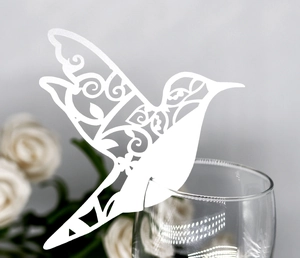 Laser cut hummingbird place card on wine glass edge with intricate vine pattern details