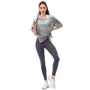 Women's loose grey sport top with side knot and purple high-waisted yoga leggings