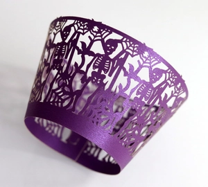 Close-up of laser-cut purple Halloween cupcake wrapper with skeleton and spider web details