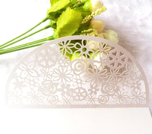 Off-white laser-cut wedding invitation card with intricate floral rose patterns
