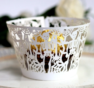 Detailed laser-cut Halloween skull and spider web pattern on a white cupcake wrapper