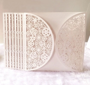 Macro shot of laser-cut floral patterns on ivory wedding invitation cards set