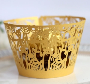 Detail of golden laser-cut Halloween cupcake wrapper with skull and spider web motifs