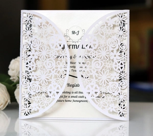 Detail of laser-cut floral lace wedding invitation with white rose decorative elements