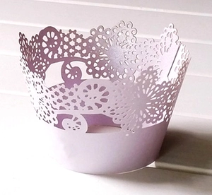 Detailed laser-cut lavender cupcake wrapper with intricate lace floral patterns on wood
