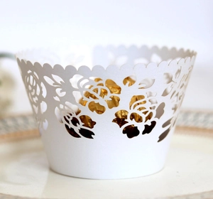 Close-up of white laser-cut rose hollow cupcake liner with a gold foil chocolate