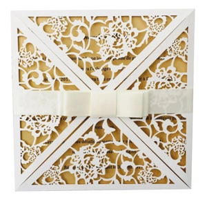 Detail of laser-cut floral wedding invitation with white ribbon and gold paper insert