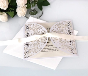Close-up of laser-cut floral wedding invitation with cream ribbon and elegant inserts