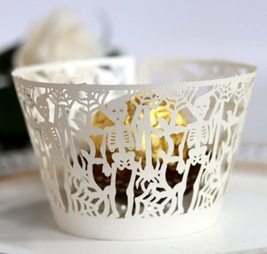 Detail of white laser-cut Halloween cupcake wrapper with skeleton and spider web patterns