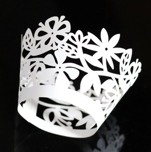 Macro shot of white floral laser-cut cupcake wrapper with intricate lace patterns