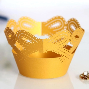 Detailed view of laser-cut gold cupcake liners with elegant swirl and hollow wave patterns