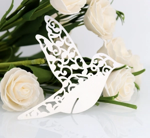 Detail of white laser-cut hummingbird paper place card showing intricate hollow patterns