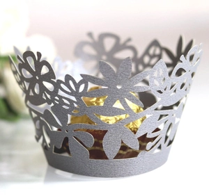 Macro shot of silver laser-cut cupcake wrapper with floral pattern and golden chocolate
