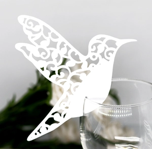Detail shot of laser-cut white hummingbird paper place card on a wine glass edge