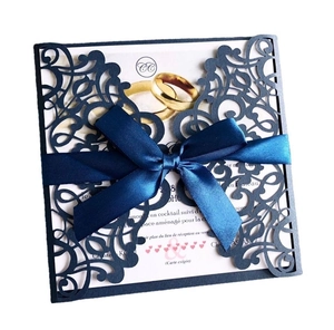 Detailed laser-cut navy wedding invitation with satin bow and golden rings design