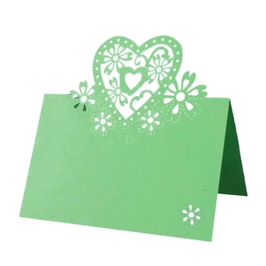 Close-up of laser-cut heart and floral details on a mint green wedding place card