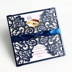Dettaglio dell'invito di nozze blu navy tagliato al laser con nastro di raso e anelli