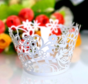 Macro shot of white laser-cut cupcake wrappers with intricate floral and vine patterns