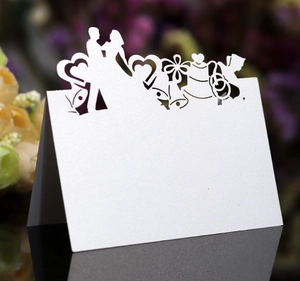 Détail d'un marque-place de mariage découpé au laser blanc nacré avec motifs et silhouettes