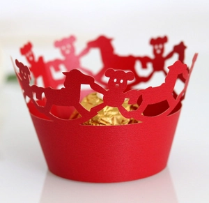Macro shot of red laser-cut cupcake wrapper with teddy bear and horse pattern