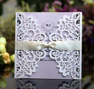 Detail of laser-cut floral wedding invitation with a pink inner card and silk ribbon bow