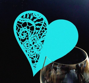 Close-up of laser-cut heart wine glass card with intricate floral lace pattern in cyan