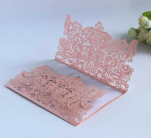 Close-up of laser-cut rose gold wedding invitation with intricate floral patterns
