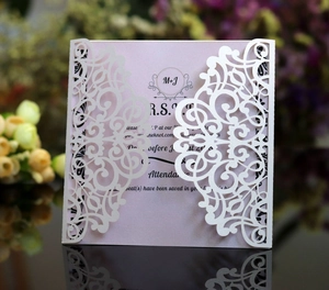 Macro view of laser-cut wedding invitation featuring a pearl white cover and RSVP card