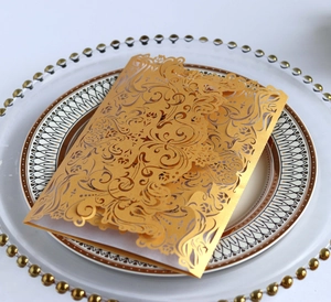 Close-up of laser-cut champagne gold invitation cover with ornate floral patterns