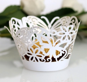 Vista de detalle de envoltorios de cupcake calados con mariposas blancas cortadas con láser