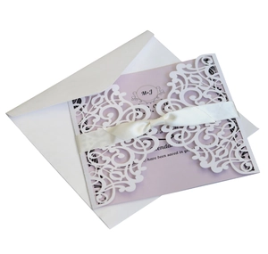 Detail of laser-cut wedding invitation with lavender card and white satin ribbon bow