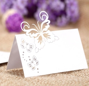 Macro view of laser-cut butterfly place card with intricate white pearlescent paper detail