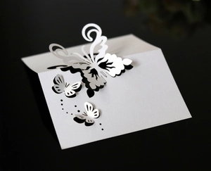 Macro shot of white laser-cut butterfly place card with 3D wings on black background