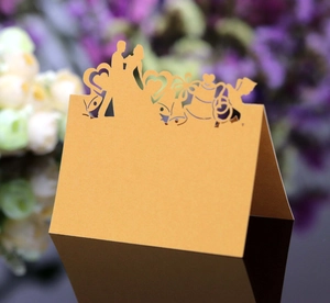 Golden laser-cut wedding place card with couple silhouette and heart-shaped patterns