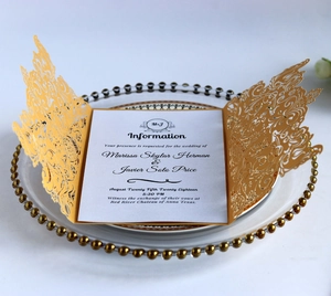Macro view of golden laser-cut hollow wedding invitation on glass tray with beads