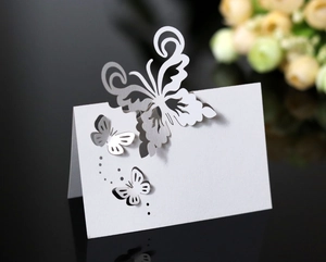 Macro shot of white laser-cut butterfly place card with intricate hollow pattern and 3D effect