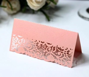 Detail of pink laser-cut lace table card with shimmering pearlescent paper texture