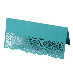 Detail view of teal laser-cut lace wedding place card with elegant hollow pattern