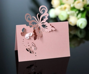 Macro detail of laser-cut pink butterfly place card on a black reflective surface