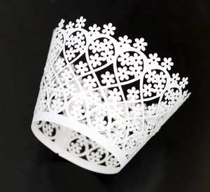 Close-up of white laser-cut cupcake wrappers with intricate floral hollow patterns