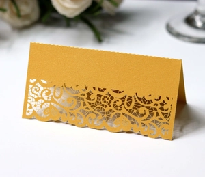 Detail of laser-cut gold lace pattern on elegant pearl paper wedding place card