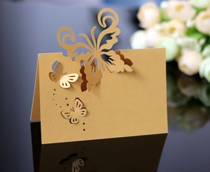 Detailed laser-cut butterfly place cards in gold pearlescent paper for wedding table decor