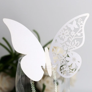 Gros plan d'une carte papillon blanche découpée au laser sur le bord d'un verre