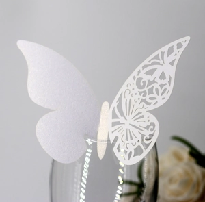 Detail of white 3D butterfly place card with laser-cut patterns on a glass rim